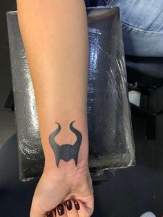 a woman's hand with a tattoo on her left arm and an elephant symbol on the wrist