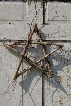 a star made out of branches on the side of a wooden door with peeling paint