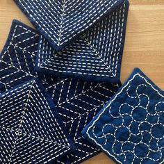 four blue napkins with white designs on them sitting on top of a wooden table