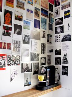 a coffee maker sitting on top of a counter next to a wall covered with pictures