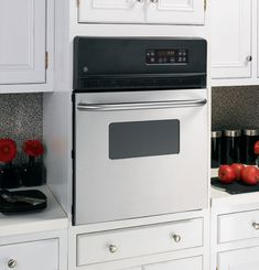 a kitchen with white cabinets and silver appliances in the corner, including apples on the counter