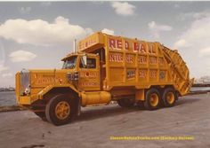 a large yellow dump truck parked on the side of a road next to some water