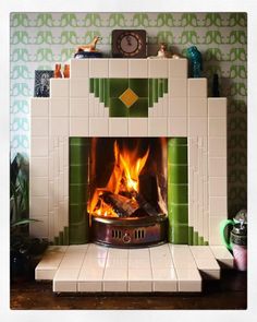 a fireplace with a fire in it and green tiles on the wall behind it,