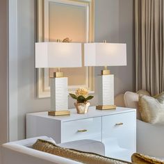 a white table with two lamps on it and a mirror in the corner behind it