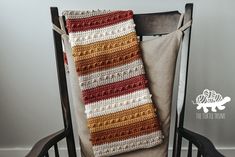 a crocheted scarf sitting on top of a wooden chair next to a pillow