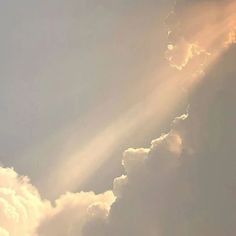 an airplane flying in the sky with sunbeams and clouds behind it on a cloudy day