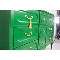 a green dresser with gold handles and knobs