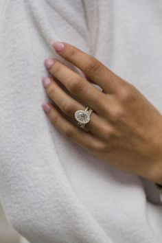 a woman's hand with a diamond ring on her left wrist, wearing a white sweater