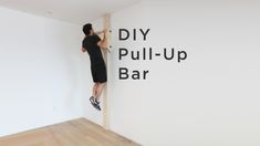 a man that is standing up against a wall with his feet in the air on a bar