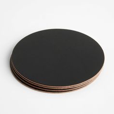 four black coasters stacked on top of each other in front of a white background