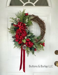 a wreath with red flowers and greenery hangs on the front door