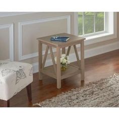 a small end table with a book on it in front of a chair and window