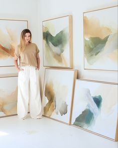 a woman standing in front of some paintings