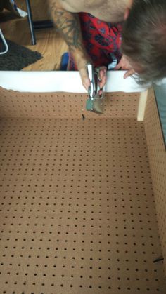 a man is using a pair of scissors to cut holes in the floor with pegs