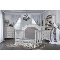 a white baby crib in a room next to a chandelier and dresser