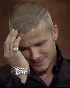 a close up of a person with a ring on his finger and wearing a black shirt