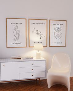 a white chair sitting next to a table with a lamp on it in front of two pictures