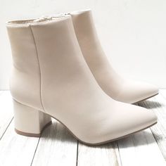 a pair of white boots sitting on top of a wooden floor