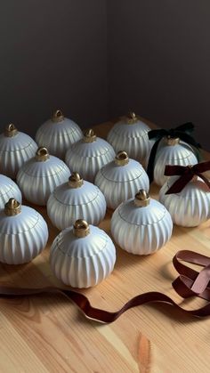 twelve white pumpkins on a wooden table with ribbon