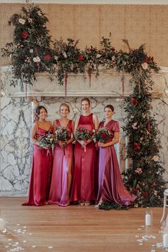 the bride and her bridesmaids pose for a photo in front of an arch decorated with greenery