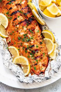 grilled salmon with lemons and parsley in foil on a white platter