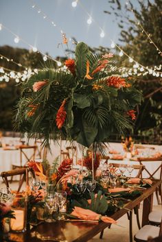 the table is set with orange flowers and greenery for an outdoor dinner or party