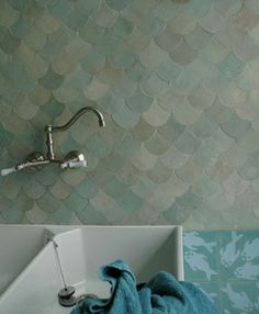 a white sink sitting under a faucet next to a green tiled bathroom wall