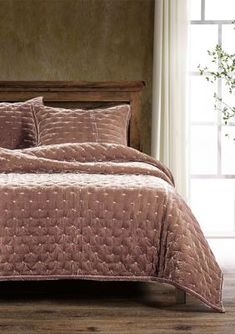 a bed covered in a pink bedspread and matching comforter set with pillows