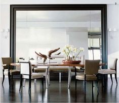 a dining room table with chairs and a mirror