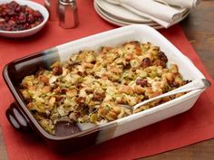 a casserole dish filled with stuffing and cranberries on a red place mat