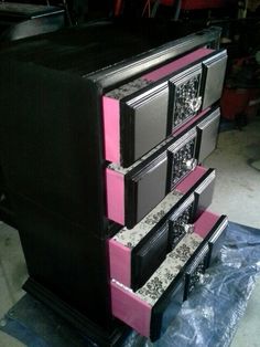 a black and pink dresser sitting on top of a table