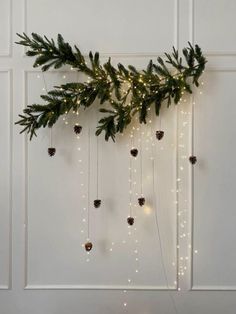 a christmas garland with pine cones and lights hanging from it