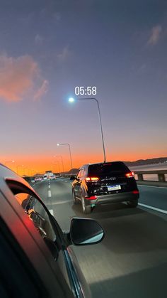 two cars are driving down the highway at sunset or dawn with an object in the distance