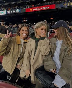 two women sitting next to each other at a baseball game and making the peace sign