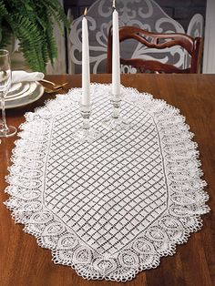 two candles are lit on a doily that is sitting on a table