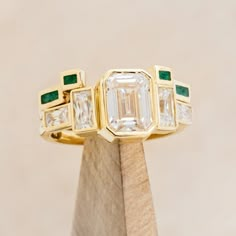 Product Details Ring Style: The Greta" is an art deco-style bezel set moissanite women's engagement ring with moissanite accent stones and a malachite stacking band. Many other center stone options are available upon request. Center Stone: 8x6mm Emerald Cut Moissanite Materials: 14K white gold engagement ring featuring 3 main moissanite stones, baguette moissanite side stones, and a malachite inlay tracer. Customizable: Because each ring is handcrafted to order, we can customize yours using unique materials, gemstones, or design features, often without any added cost! We can even use personal materials that you send! Basic customizations, such as material swaps, can be accommodated by simply adding a request in the “Custom Requests” section during checkout. For more extensive customization Unique Bezel Set Engagement Ring, Brand Identity Jewelry, Engagement Ring Stack, Non Traditional Wedding Ring, Emerald Cut Moissanite Engagement Ring, Emerald Wedding Band, Bezel Set Engagement Ring, Art Deco Wedding Band, Bezel Engagement Ring