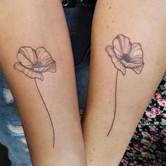 two women with matching tattoos on their legs, one has a flower and the other has a leaf