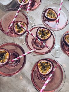 several glasses filled with desserts on top of a white table next to two pink striped straws