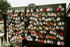 there are many mugs hanging on the wall next to each other in front of a fence