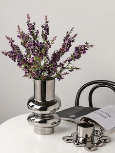 purple flowers in a silver vase on a white table