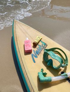 the surfboard is laying on the beach next to the water and some items that have been placed on it