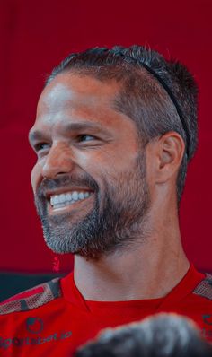 a close up of a person wearing a red shirt with a goatee and beard