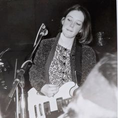 a woman is playing an electric guitar in front of a microphone and another person behind her