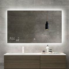 a bathroom vanity with a large mirror above it and lights on the wall behind it