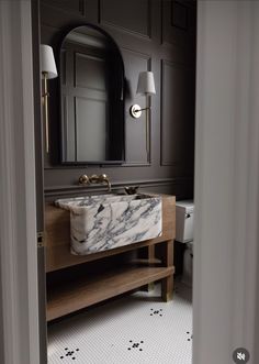 a bathroom with a marble sink and wooden cabinet in the corner, along with two lamps on either side