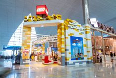 the entrance to an indoor shopping mall with legos on it's walls and people walking around