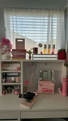 a white desk topped with lots of clutter next to a window covered in blinds