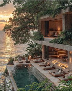 an outdoor swimming pool next to the ocean with lounge chairs and candles lit on it