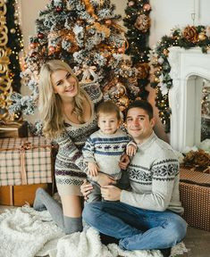 a man, woman and child sitting in front of a christmas tree