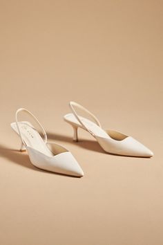 two white shoes on top of a beige surface with one shoe in the foreground